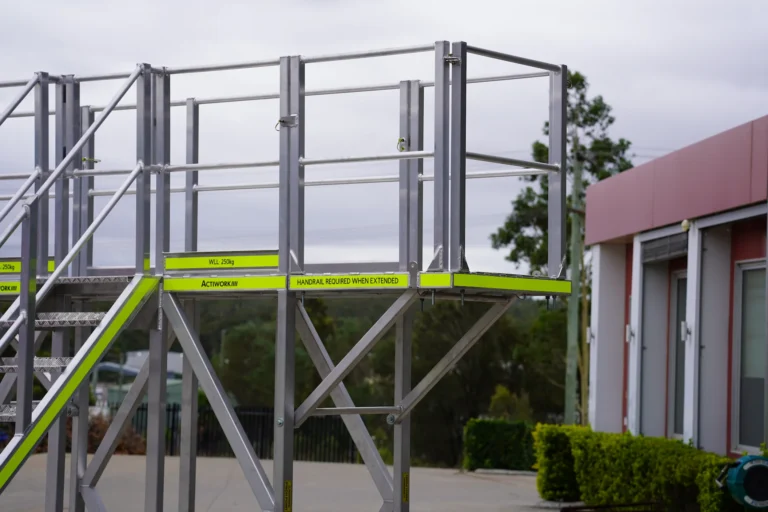 Adjustable industrial access platform with handrails and stair access for safe maintenance and elevated work environments.